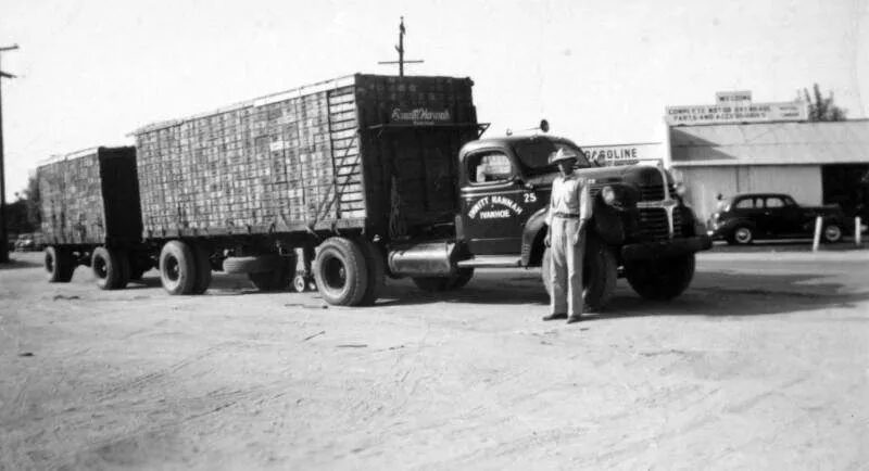 A man standing next to a truck with a trailer.