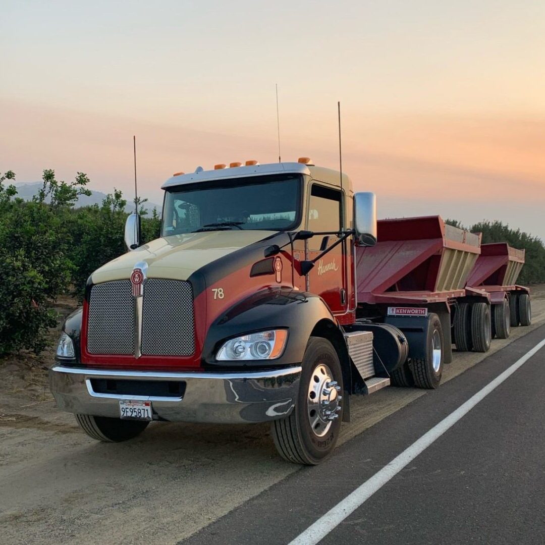 A red truck is driving down the road