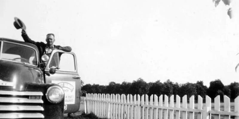 A man riding in the back of an old truck.